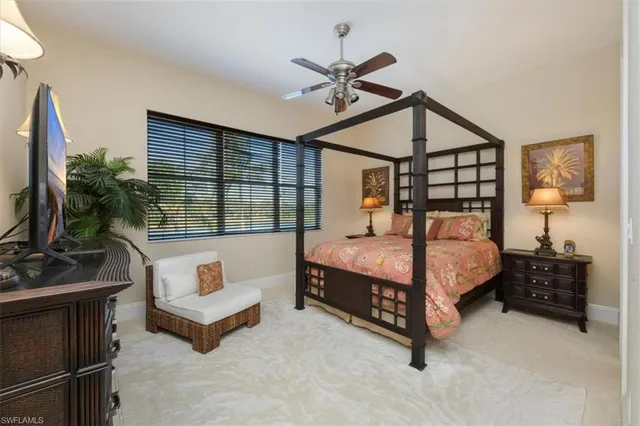 a bedroom with a bed a couch and a flat tv screen on the dresser