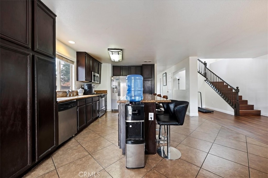 16220 Vía Ultimo Moreno Valley, CA 92551 - Photo 15 of 38 a kitchen with stainless steel appliances kitchen island granite countertop a refrigerator and cabinets