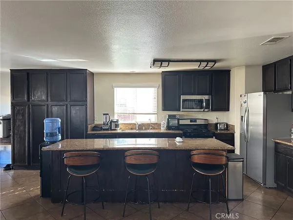 a kitchen with stainless steel appliances granite countertop a sink a stove a refrigerator cabinets and chairs