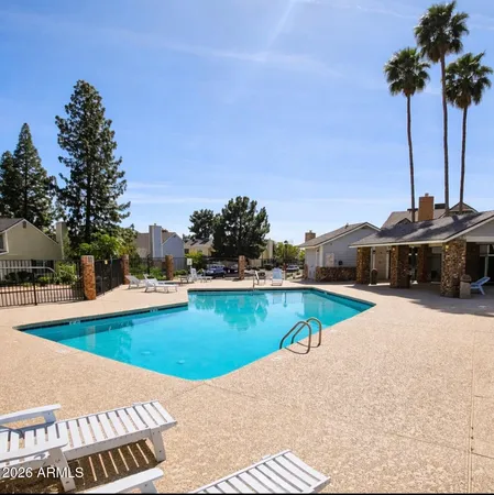 a view of a swimming pool with lawn chairs under an umbrella