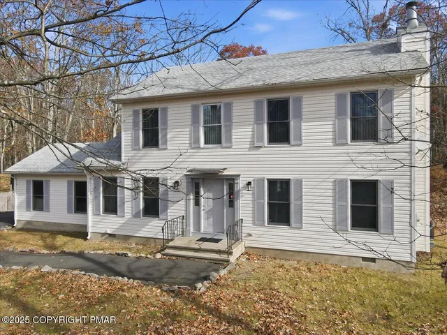 a view of a white house with large windows next to a yard