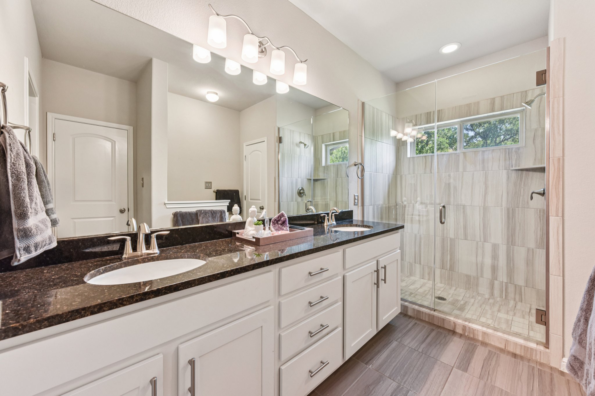 908 Goldilocks Lane Manchaca, TX 78652 - Photo 17 of 34 This delightful ensuite has a windowed shower enclosed by frameless glass and a double vanity.