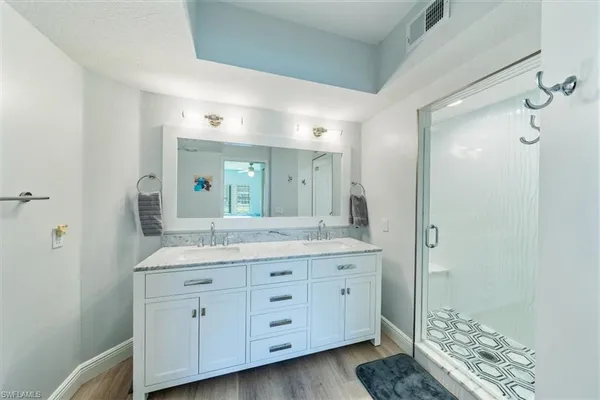 a spacious bathroom with a granite countertop sink a mirror and a shower
