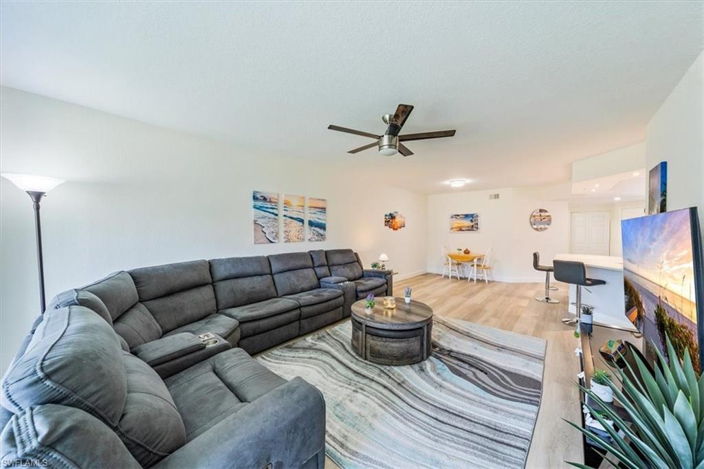 6914 Satinleaf Road North, Unit 103 Naples, FL 34109 - Photo 3 of 34 a living room with furniture kitchen view and a flat screen tv