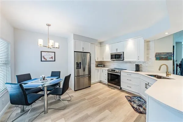 a kitchen with a refrigerator a stove a sink a dining table and chairs