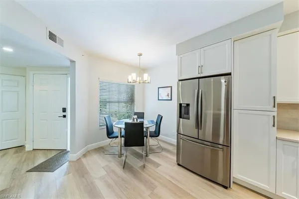 a kitchen with stainless steel appliances a refrigerator a stove a dining table and chairs