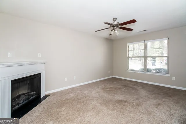 a view of an empty room with window and fireplace