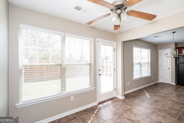 a view of an empty room with a window and a chandelier fan