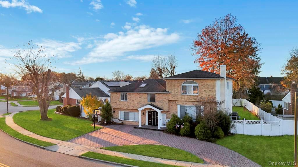 View of front of house featuring a chimney, brick siding, decorative driveway, and a residential view