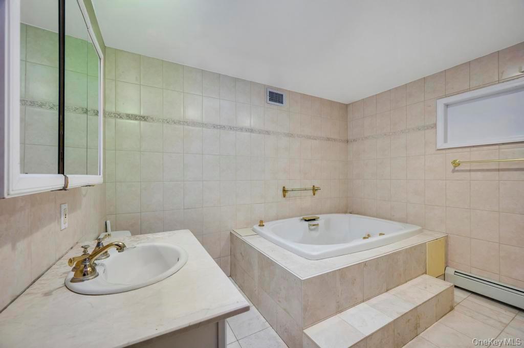 64 Fox Place Hicksville, NY 11801 - Photo 11 of 25 Bathroom with vanity, a jetted tub, light tile patterned floors, and tile walls