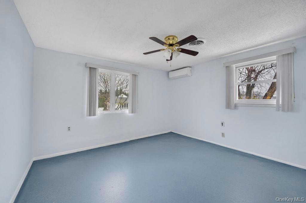 64 Fox Place Hicksville, NY 11801 - Photo 15 of 25 Spare room featuring a ceiling fan, a wall unit AC, and a textured ceiling