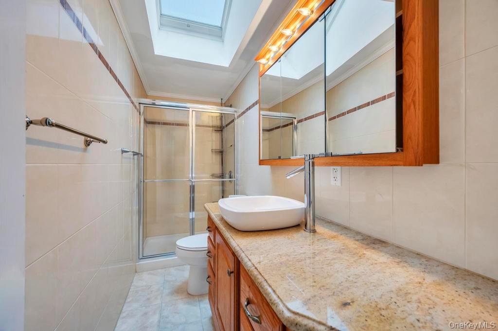 64 Fox Place Hicksville, NY 11801 - Photo 16 of 25 Full bathroom with a skylight, a shower stall, vanity, crown molding, and tile walls