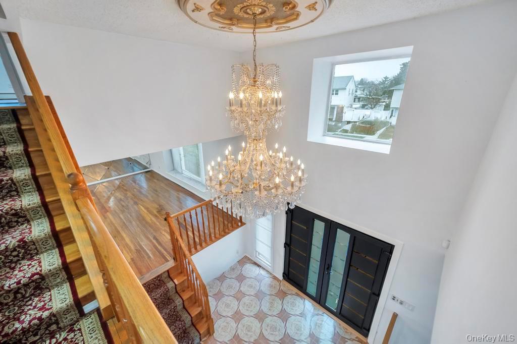64 Fox Place Hicksville, NY 11801 - Photo 3 of 25 Entrance foyer featuring a chandelier, stairway, a high ceiling, and a textured ceiling
