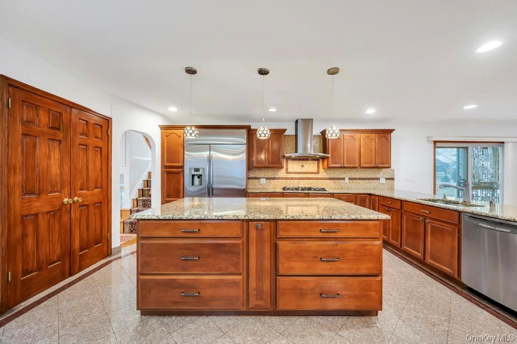 64 Fox Place Hicksville, NY 11801 - Photo 6 of 25 Kitchen featuring granite floors, a kitchen island, appliances with stainless steel finishes, arched walkways, and light stone counters