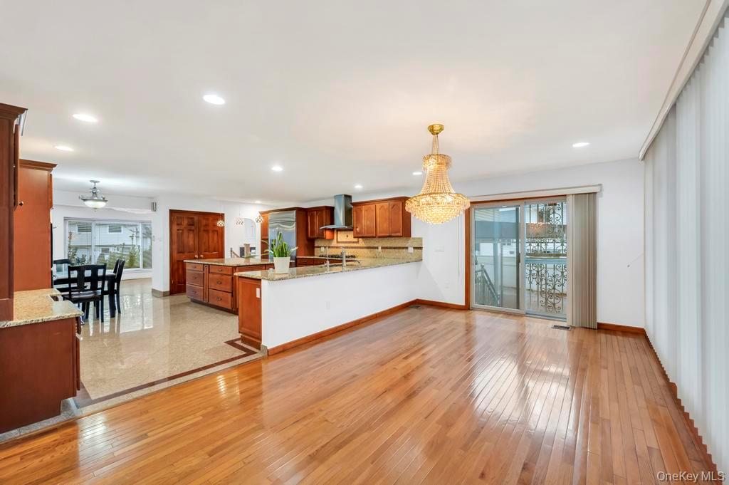 64 Fox Place Hicksville, NY 11801 - Photo 7 of 25 Kitchen featuring light stone counters, a peninsula, brown cabinets, recessed lighting, and light wood-style floors