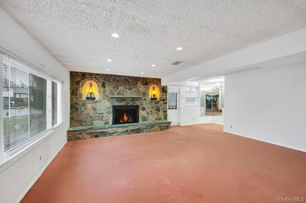 64 Fox Place Hicksville, NY 11801 - Photo 8 of 25 Unfurnished living room with a textured ceiling, a fireplace, carpet floors, a chandelier, and recessed lighting