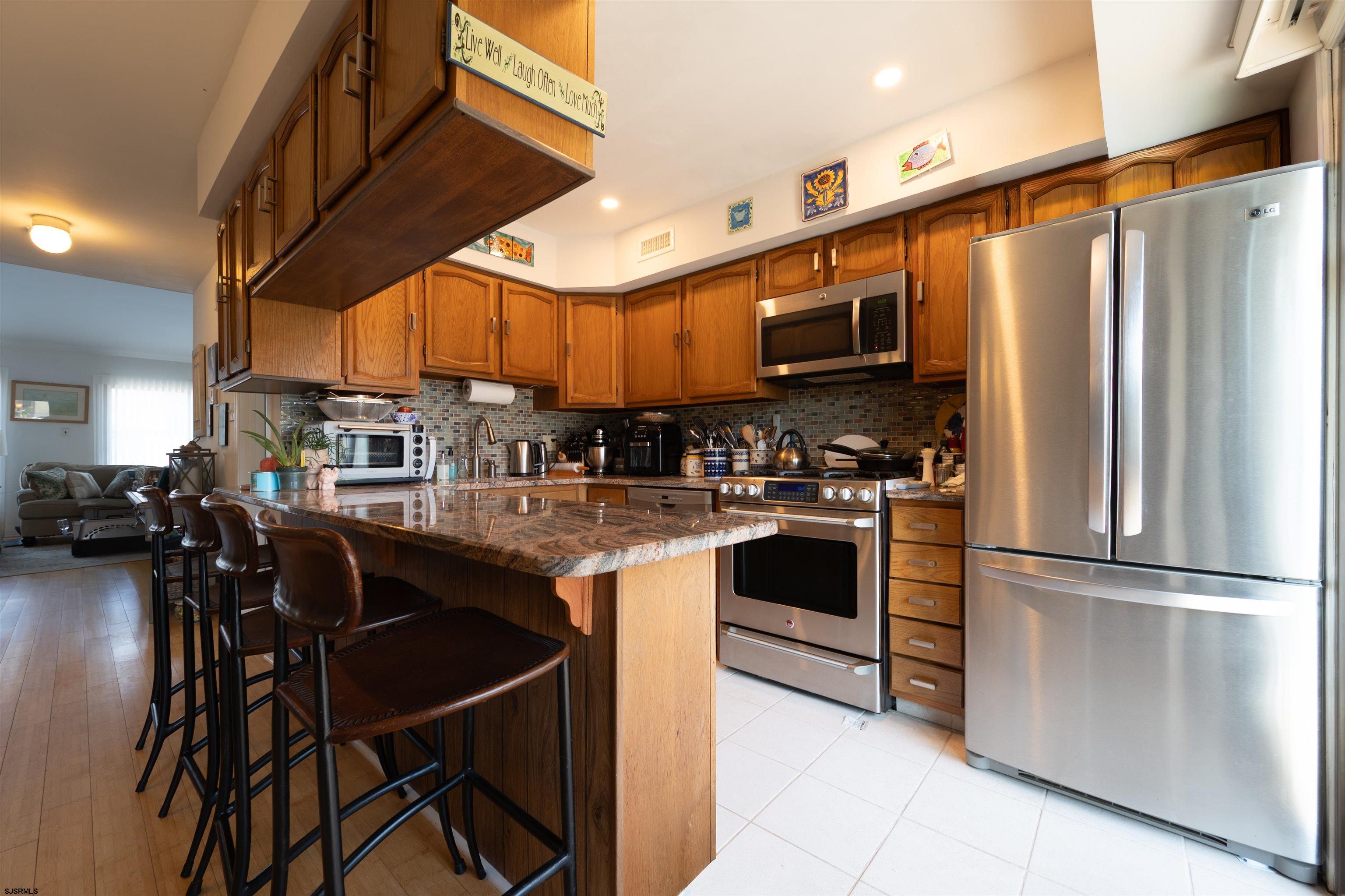 19 Bramble Drive Brigantine, NJ 08203 - Photo 11 of 15 a kitchen with stainless steel appliances kitchen island granite countertop a refrigerator and microwave