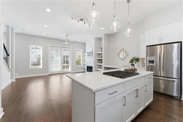 a kitchen with a stove a refrigerator a sink and white cabinets with wooden floor