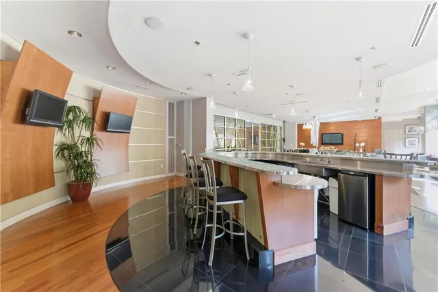 a kitchen with stainless steel appliances granite countertop a stove top oven a refrigerator a dining table and chairs with wooden floor