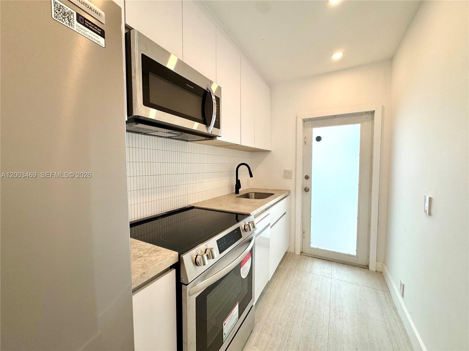 6944 Byron Avenue, Unit 1 Miami Beach, FL 33141 - Photo 11 of 15 a view of a kitchen with a sink and a microwave