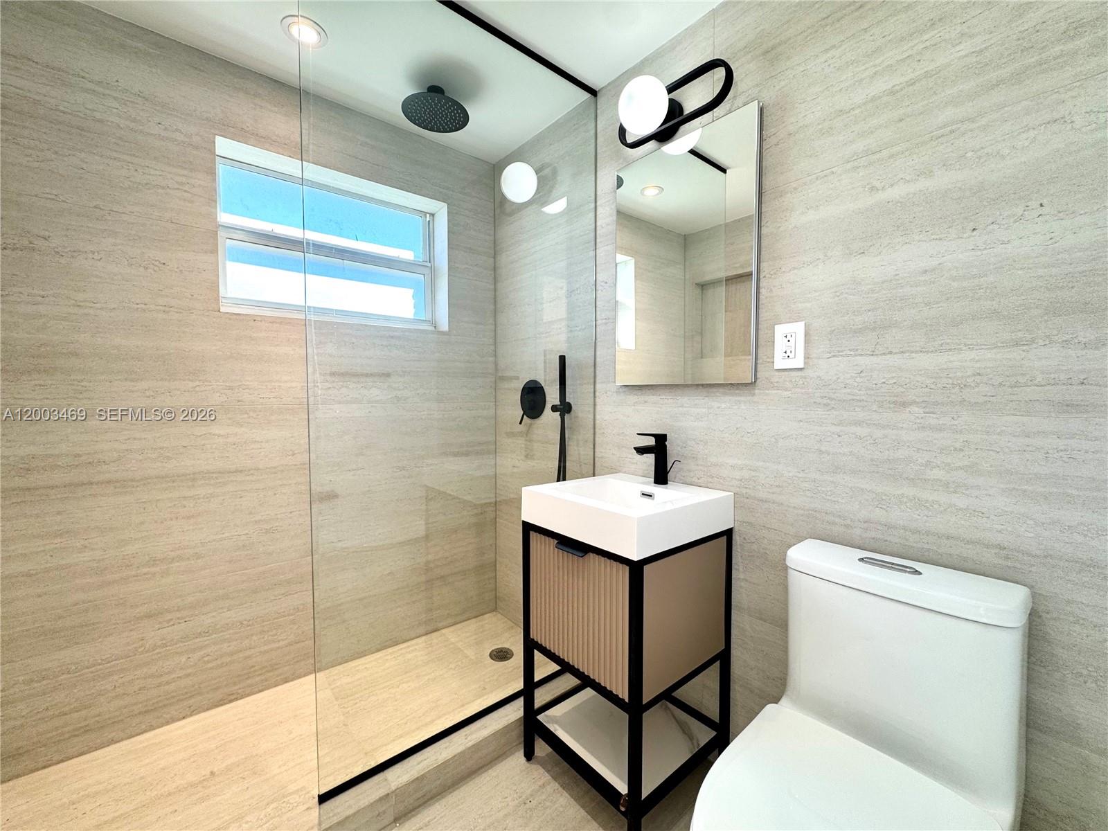 6944 Byron Avenue, Unit 1 Miami Beach, FL 33141 - Photo 6 of 15 a bathroom with a sink a toilet and mirror
