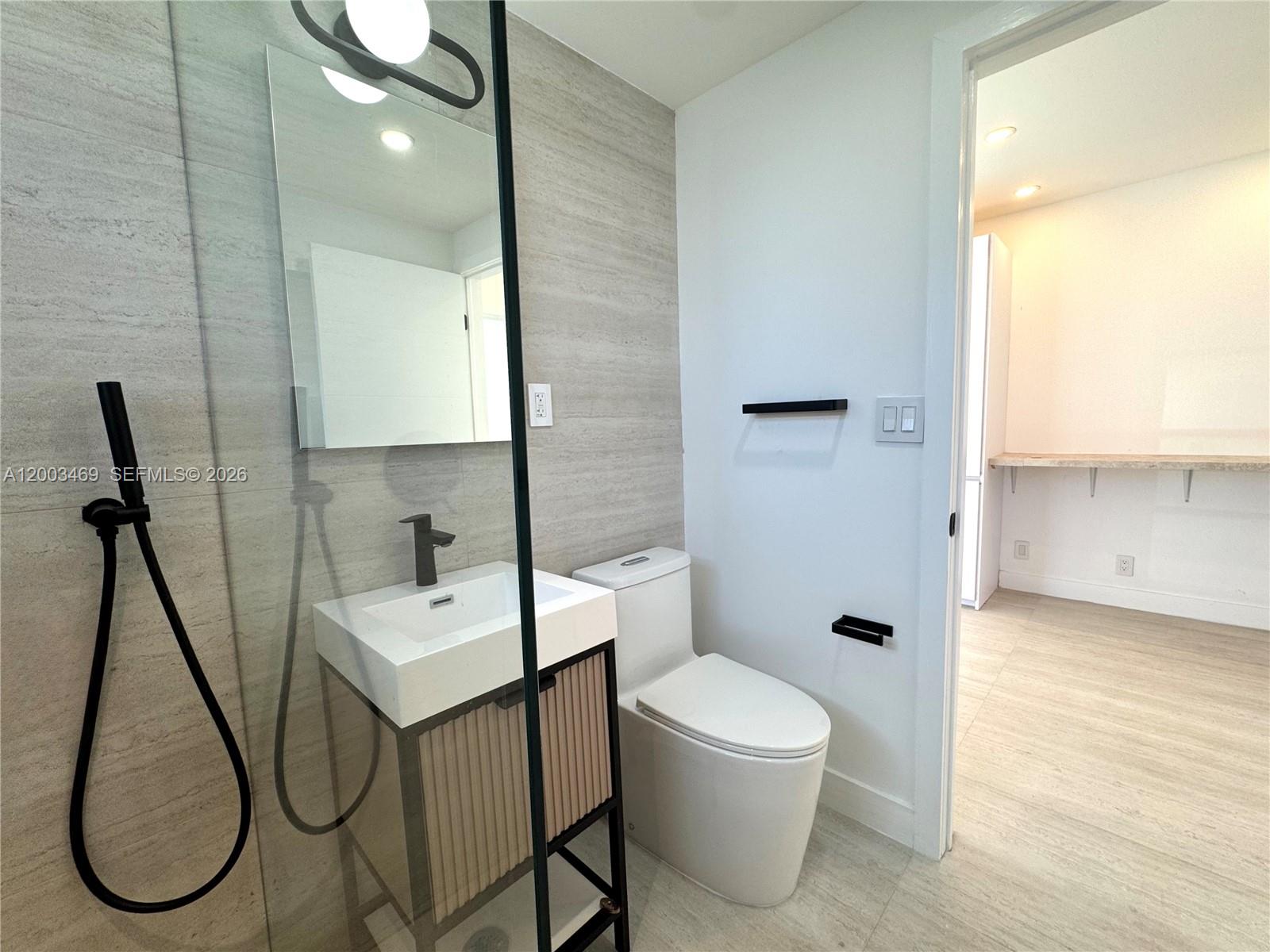 6944 Byron Avenue, Unit 1 Miami Beach, FL 33141 - Photo 7 of 15 a bathroom with a toilet sink a shower and mirror
