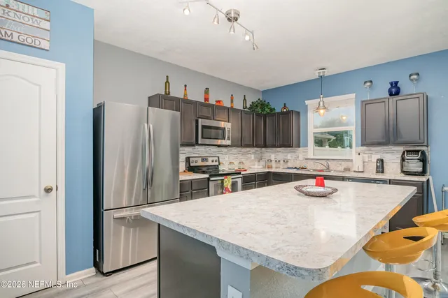 a kitchen with stainless steel appliances granite countertop a sink refrigerator and microwave