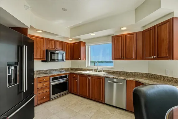 a kitchen with stainless steel appliances granite countertop sink stove refrigerator and cabinets