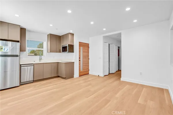a large white kitchen with kitchen island a sink stainless steel appliances and cabinets