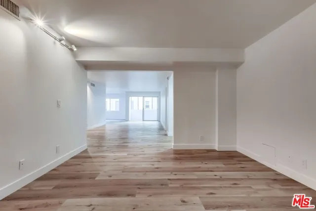a view of an empty room with wooden floor and window