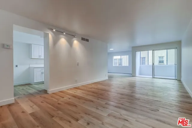 a view of empty room with wooden floor and fan