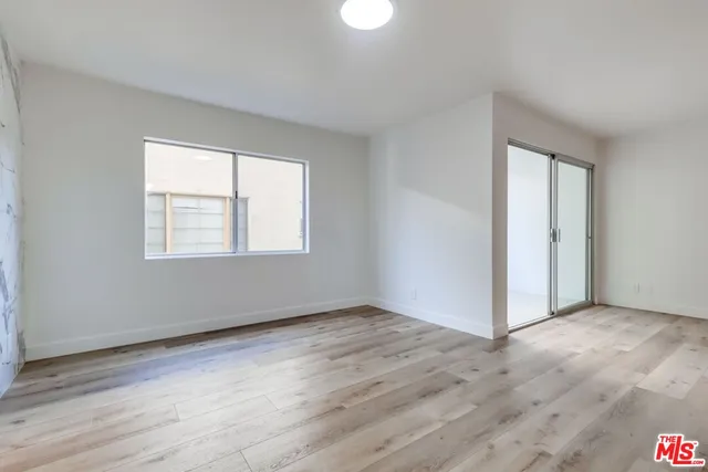 an empty room with wooden floor cabinet and windows
