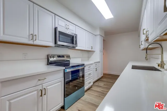 a large kitchen with stainless steel appliances granite countertop lots of counter space and a sink