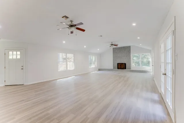 an empty room with wooden floor a ceiling fan windows and a ceiling fan