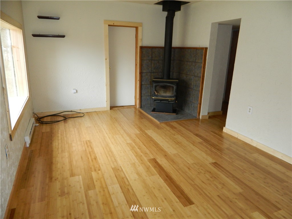 103 Cooper Street Riverside, WA 98849 - Photo 3 of 12 a view of an empty room with a fireplace and wooden floor