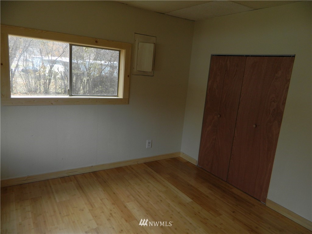 103 Cooper Street Riverside, WA 98849 - Photo 6 of 12 an empty room with wooden floor and windows