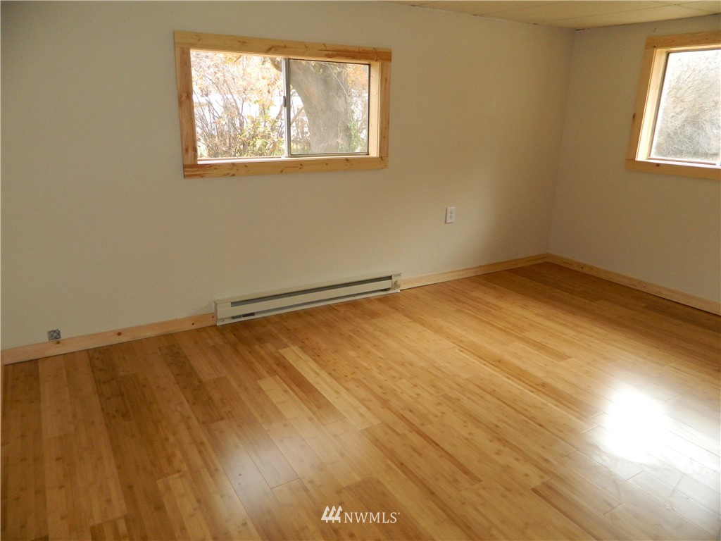 103 Cooper Street Riverside, WA 98849 - Photo 7 of 12 an empty room with wooden floor and windows