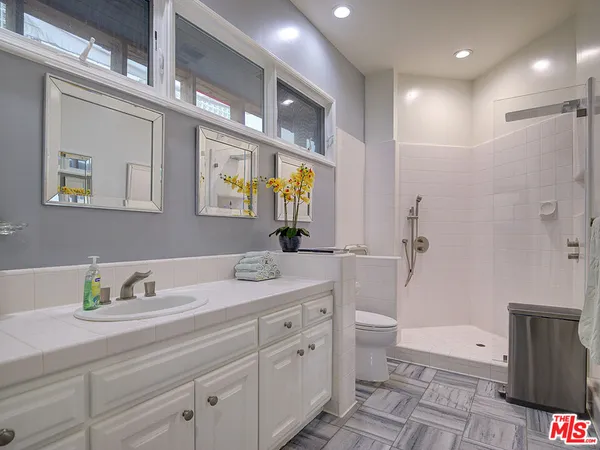 a spacious bathroom with double vanity a mirror and a shower