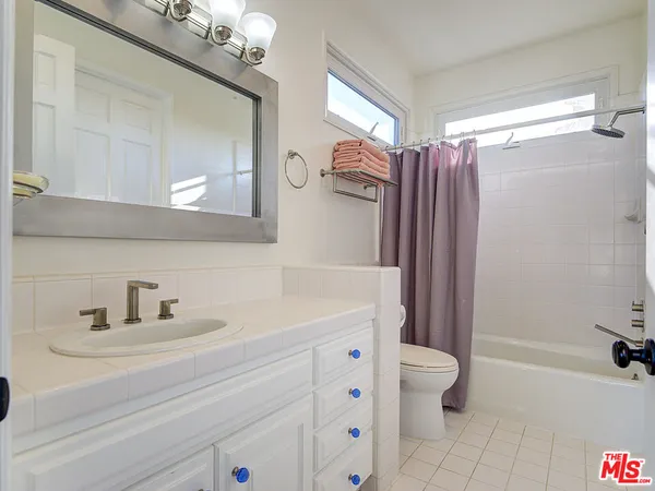 a bathroom with a sink a toilet a mirror a vanity and shower