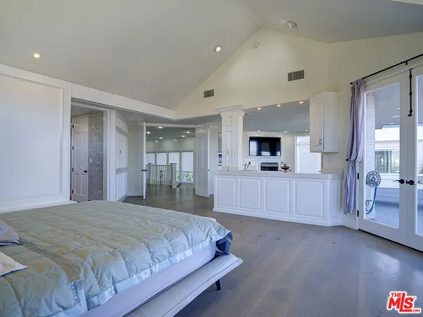 a spacious bedroom with a bed and a flat screen tv