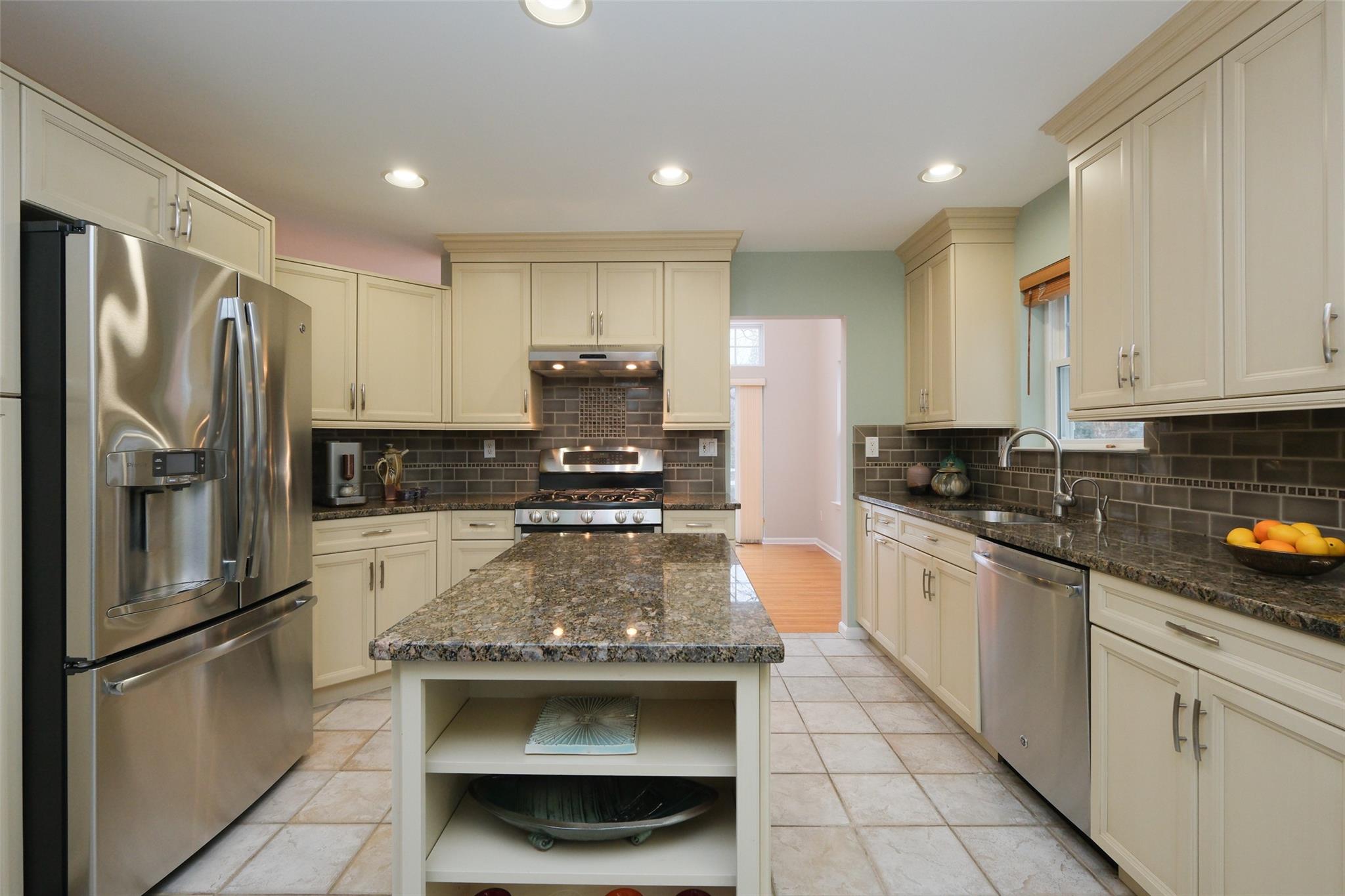 a kitchen with stainless steel appliances granite countertop a refrigerator a stove and a sink
