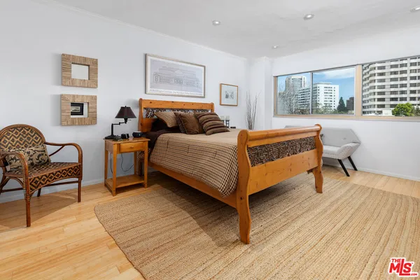 a bedroom with a bed chair and wooden floor
