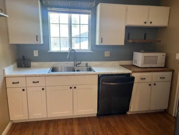 a kitchen with granite countertop white cabinets and sink