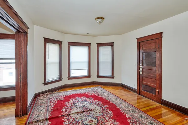 a view of an empty room with window and wooden floor