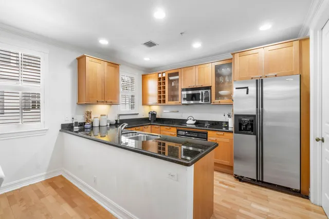 a kitchen with stainless steel appliances granite countertop a refrigerator a sink a stove a washer dryer and a refrigerator