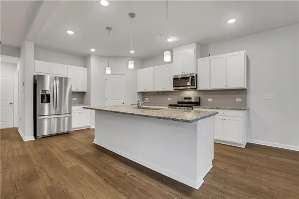 a kitchen with granite countertop a refrigerator and a stove top oven