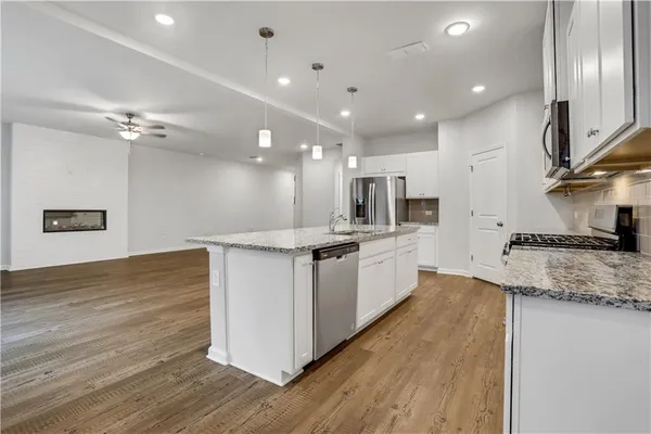a large kitchen with stainless steel appliances kitchen island a large counter top and a wooden floors