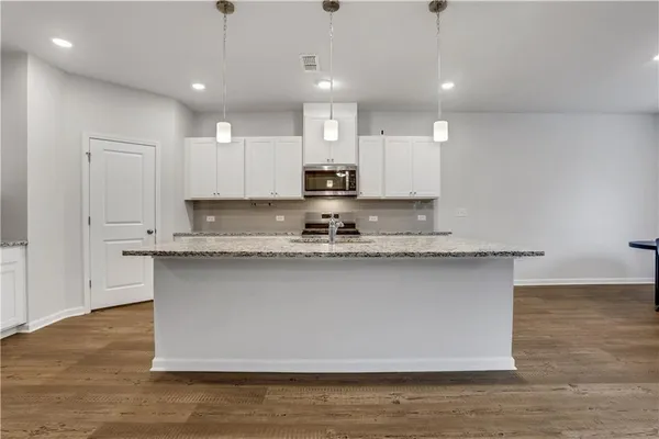 a kitchen with granite countertop a stove a sink and a refrigerator