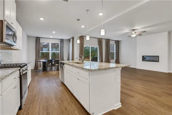 a large kitchen with stainless steel appliances granite countertop a lot of counter space and wooden floors