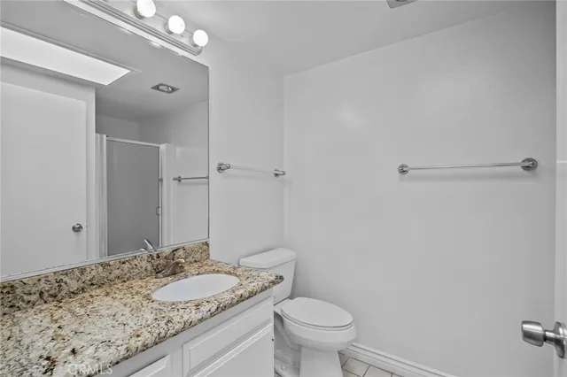 a bathroom with a granite countertop sink a toilet and a mirror